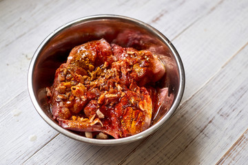 Raw rabbit in a bowl with spices. Marinate meat, preparing for cooking.