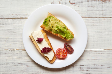 Toasted baguette with avocado, tomato and cheese. on a light wooden background.