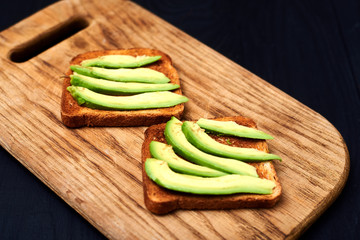 Toast with sliced avocado on a wooden background.
