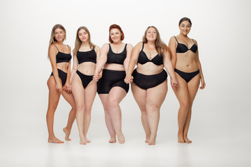 In love with myself. Portrait of beautiful young women with different shapes posing on white background. Happy female models. Concept of body positive, beauty, fashion, style, feminism. Diversity.