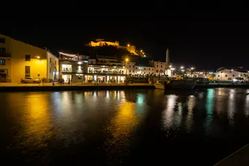 Foto op Plexiglas Tuscany Maremma Castiglione della Pescaia, fireworks over the sea, panoramic night view of the port and the castle © Roberto
