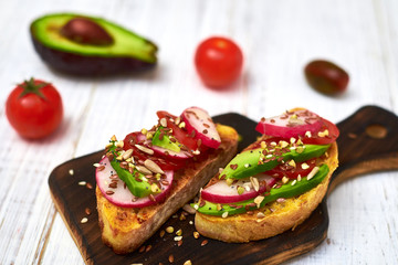 Toasts with vegetables, avocado, tomatoes, a set of seeds on a white background. Healthy food, diet concept.