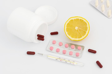 Jar for pills, blister with orange pills, lemon and thermometer, brown capsules.