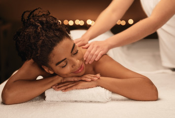 Obraz na płótnie Canvas Young black woman getting relaxing massage at spa