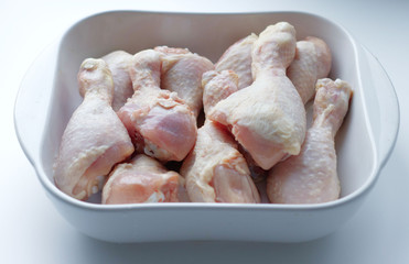 chicken thighs with skin, in a white glass plate, on a gray background. Ingredients, fresh, cut meat for cooking. Chicken parts, protein. Diet meat, fillet in a plate