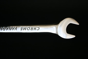 a chrome wrench tool on a black background