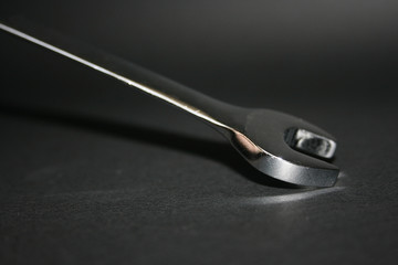 a chrome wrench tool on a black background