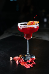 Making cocktails at home like an expert nightclub barman. Fresh and juicy colorful homemade cocktails garnished with berries, orange, cherry  on dark background.