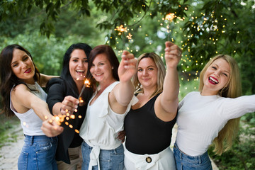 Group of girls friends having good time together with bengal lights