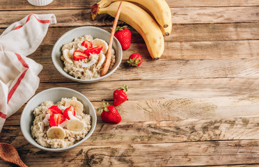 Quinoa porridge with coconut milk and fresh strawberries on wooden rustic background. Healthy Lactose and Gluten Free Breakfast.