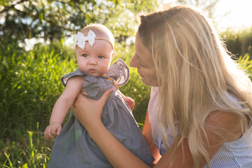 Happy mother with little daughter spending time together in sunny field
