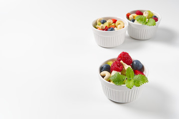 Bowl of healthy fresh fruit salad on white background, side view copy space.