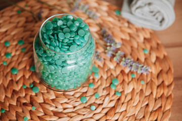 Blue  wax drops of sugaring paste in the transparent jar on the wooden background with lavender....