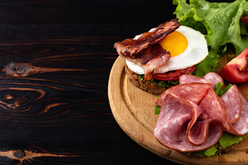 ham and egg bacon sandwich on dark wooden background with copy space