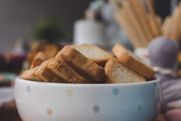 Wheat flour mini toast in a clay bowl, birthday party background. Square croutons in a white bowl...