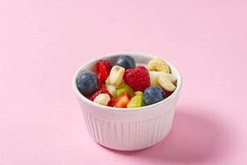 Bowl of healthy fresh fruit salad on pink background, side view copy space. modern fresh fruit salad apperatriv.