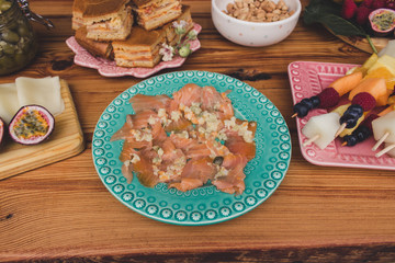 Variety of food on rustic wooden table, top view. Smoked Salmon canapes in vintage plate. Party concept.