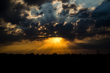 The Golden rays of the sun pass through the clouds in the evening sky. The time of sunset.