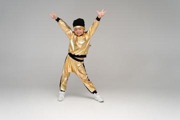 Fototapeta na wymiar Happy little girl in gold suit dancing isolated on white background