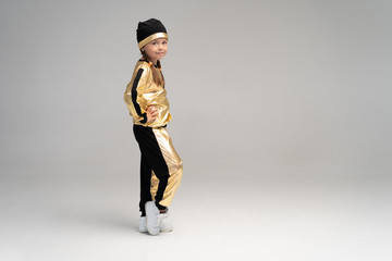 Happy little girl in gold suit dancing isolated on white background
