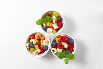 Bowl of healthy fresh fruit salad on white background, top view copy space.