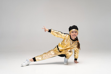 Happy little girl in gold suit dancing isolated on white background