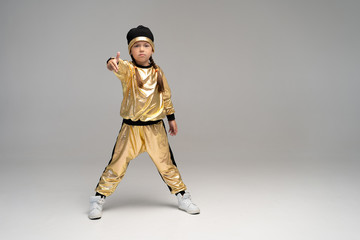 Happy little girl in gold suit dancing isolated on white background