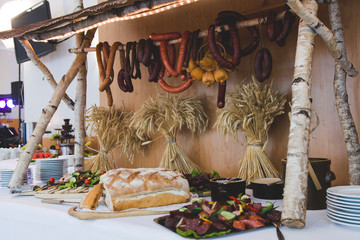 Stoisko z tradycyjnym polskim, słowiańskim jedzeniem. Stół biesiadny z kiełbasami, chlebem i smalcem. Tradycyjne potrawy podczas wesel - obrazy, fototapety, plakaty