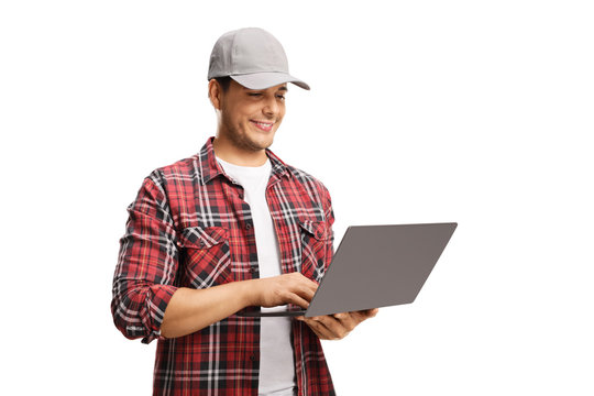 Young man with a cap and a checkered shirt working on a laptop computer
