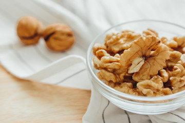 
Walnut kernels in a bowl lie on the kitchen table, close-up. Healthy food, vegetable protein source.
