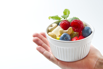 Bowl of healthy fresh fruit salad on women hand side view copy space. modern fruit salad white background,
