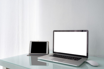 Blank screen of laptop computer and Tablet on table with white wall and white curtain