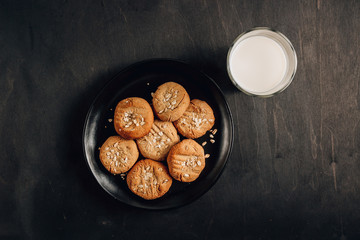Gluten free homemade oatmeal cookies and oat milk on a dark background.