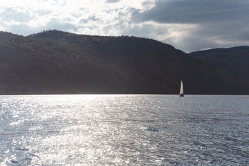 blue water with a sailing boat floating in the distance no a sunset