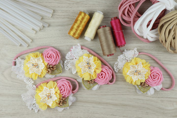 A bouquet of flowers made out of fabric cloth textile in beautiful pastel colors placed on white wooden table that can be used as hair accessory, decoration, and embellishment