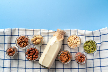 Top view of vegetable milk bottle with bowls of nuts