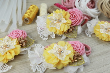 A bouquet of flowers made out of fabric cloth textile in beautiful pastel colors placed on white wooden table that can be used as hair accessory, decoration, and embellishment