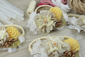 Obraz na płótnie Canvas A bouquet of flowers made out of fabric cloth textile in beautiful pastel colors placed on white wooden table that can be used as hair accessory, decoration, and embellishment