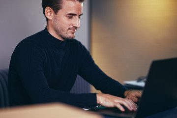 Young businessman smiling while working on a laptop