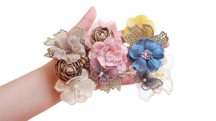 A hand holding bouquet of flowers made out of fabric cloth textile in beautiful pastel colors that can be used as hair accessory, decoration, and embellishment with white background isolated