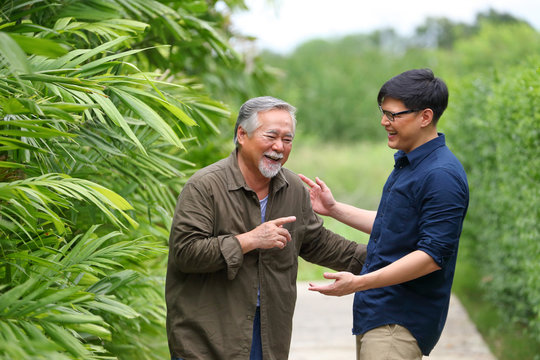 Senior Asian man laughing out loud with his boy while talking about funny memory they share together as father and son with copy space