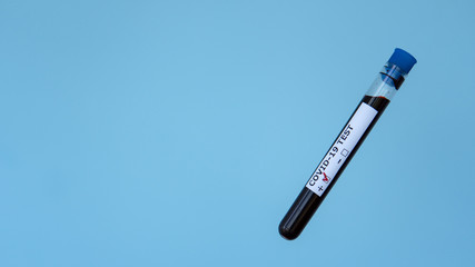 Positive test result from Coronavirus Covid-19. Test tube with fresh blood sample, isolated on blue background. Test tube levitates in air. Copy space photo.