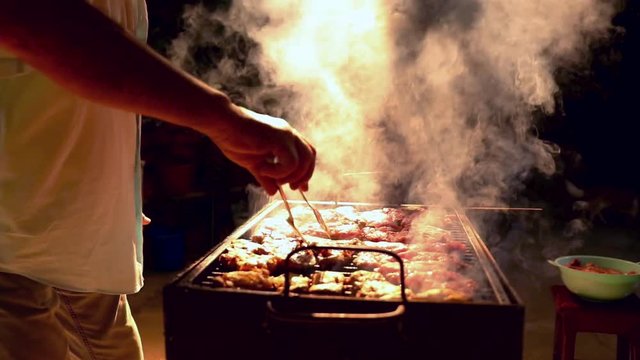 A man making a grill with meat food and fire