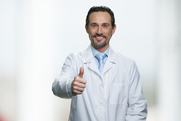 Happy doctor or scientist showing thumb up gesture. Caucasian man in white coat giving thumb up symbol to camera. Good job concept.