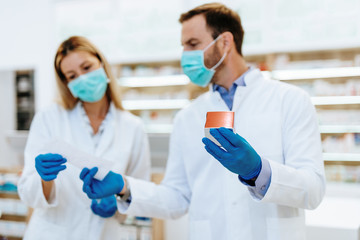 Female  and male pharmacists with protective mask on their faces working at pharmacy. Medical healthcare concept.