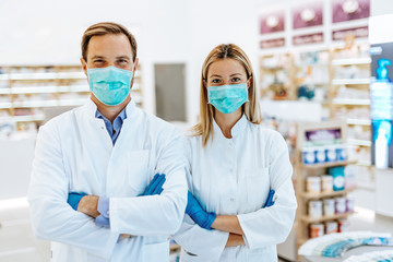 Female  and male pharmacists with protective mask on their faces working at pharmacy. Medical...