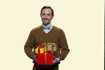 Smiling mature man holding stack of gift boxes. Handsome man with wrapped gift boxes on white background. Space for text.