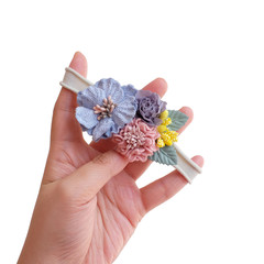 A hand holding bouquet of flowers made out of fabric cloth textile in beautiful soft pastel colors that can be used as hair accessory, decoration, and embellishment