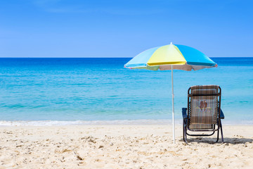 Relaxing on beach chair under colorful umbrella on white sand beach, summer outdoor day light, holiday season to South of Thailand, tropical island