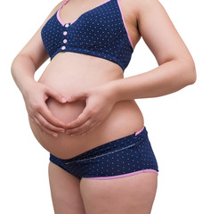 Pregnant Woman holding her hands in a heart shape on her stomach.